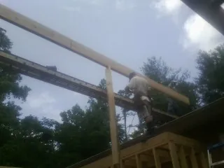 Carpenter setting a ridge beam over a new addition frame — Ice Dam Removal by Roofing Brothers in Suwannee