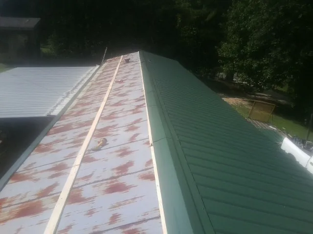 Old rusted panels beside newly installed green metal roofing — Wind Damage Roof Repair by Roofing Brothers in Suwannee