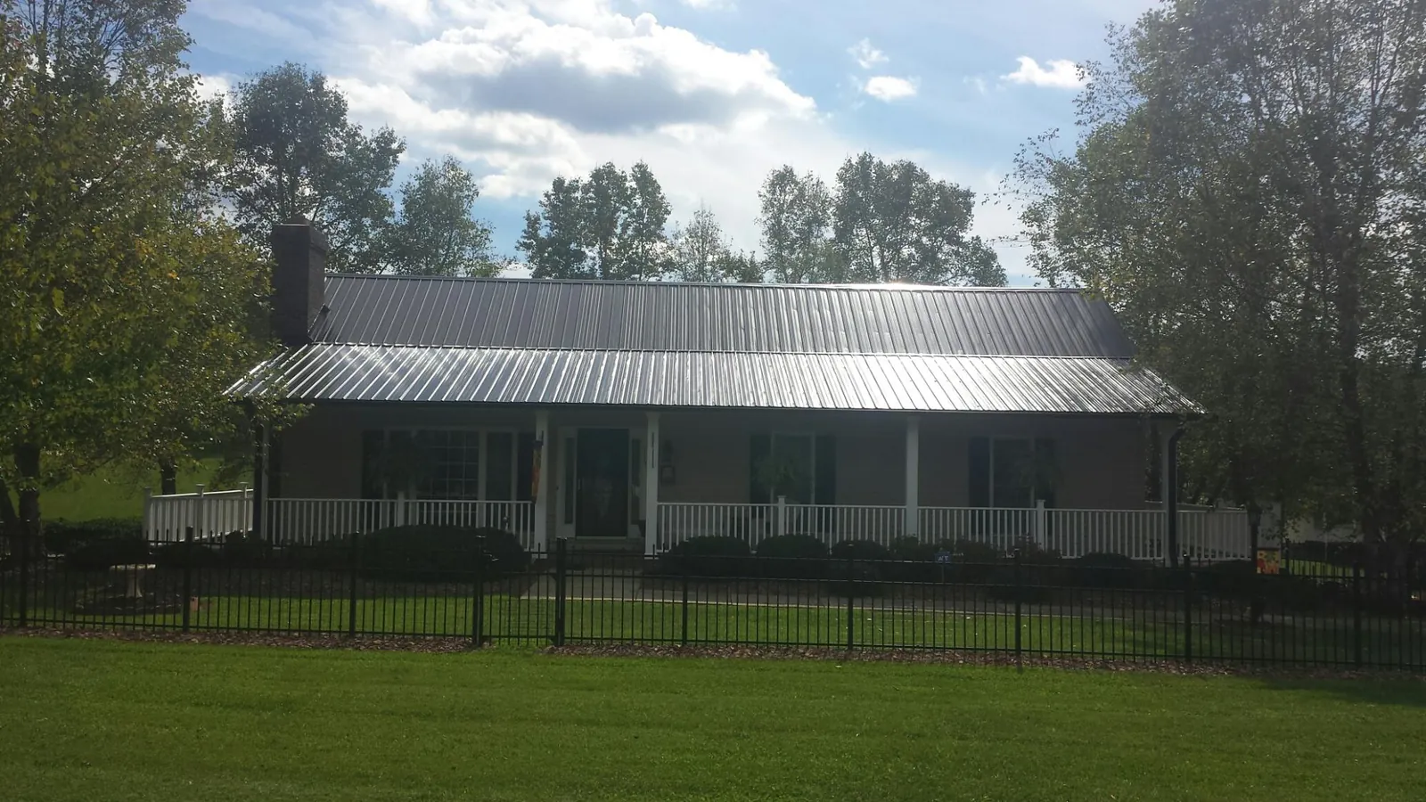 Gray metal roof on a brick ranch with a full width front porch — Gutter Guard Installation work by our crew in Suwannee