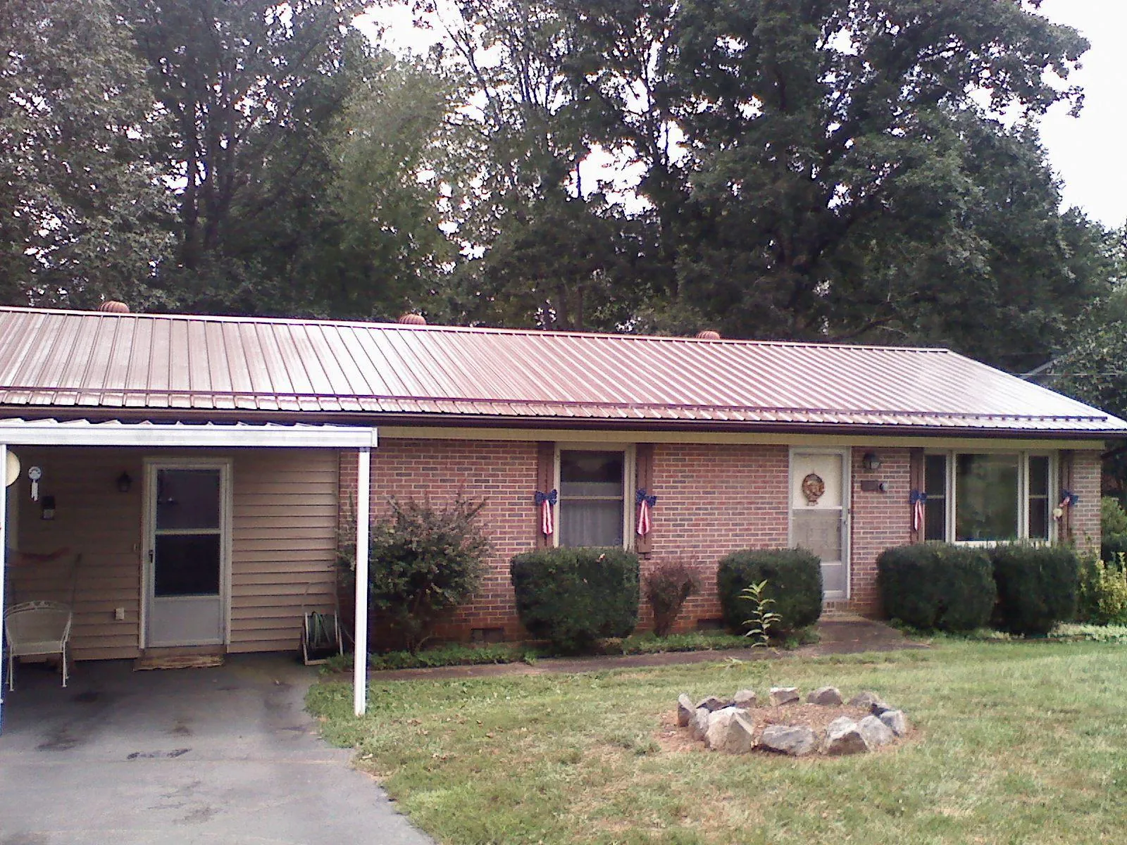 Bronze metal roof and carport on a brick ranch home — Roof Repair work by our crew in Suwannee